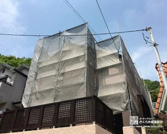 外壁塗装の工事中に足場と飛散防止シートで覆われた住宅
